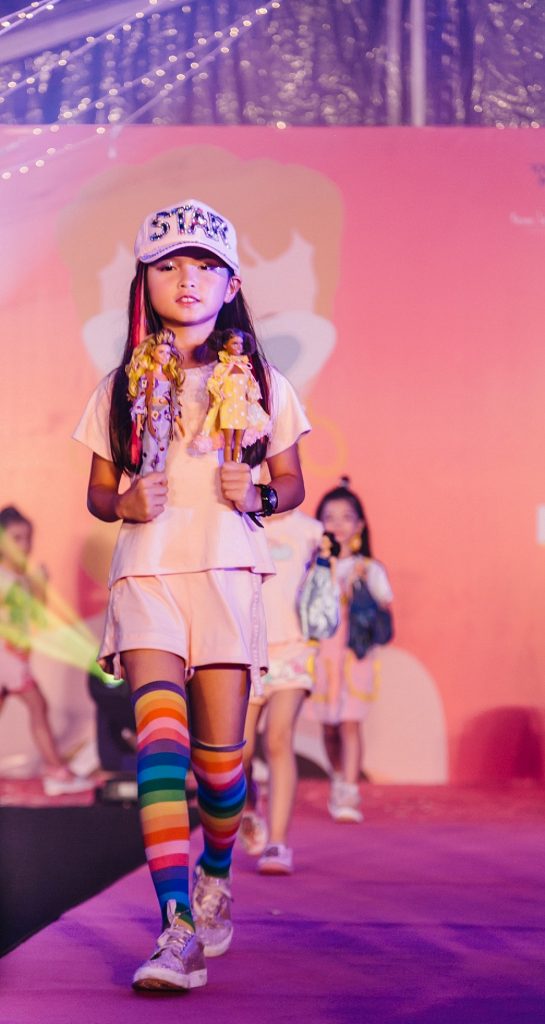 A Junior Supermodel from the Amber Chia Academy showcasing the Custom Styled Barbie Dolls by students of Limkokwing University and the A Cut Above Academy