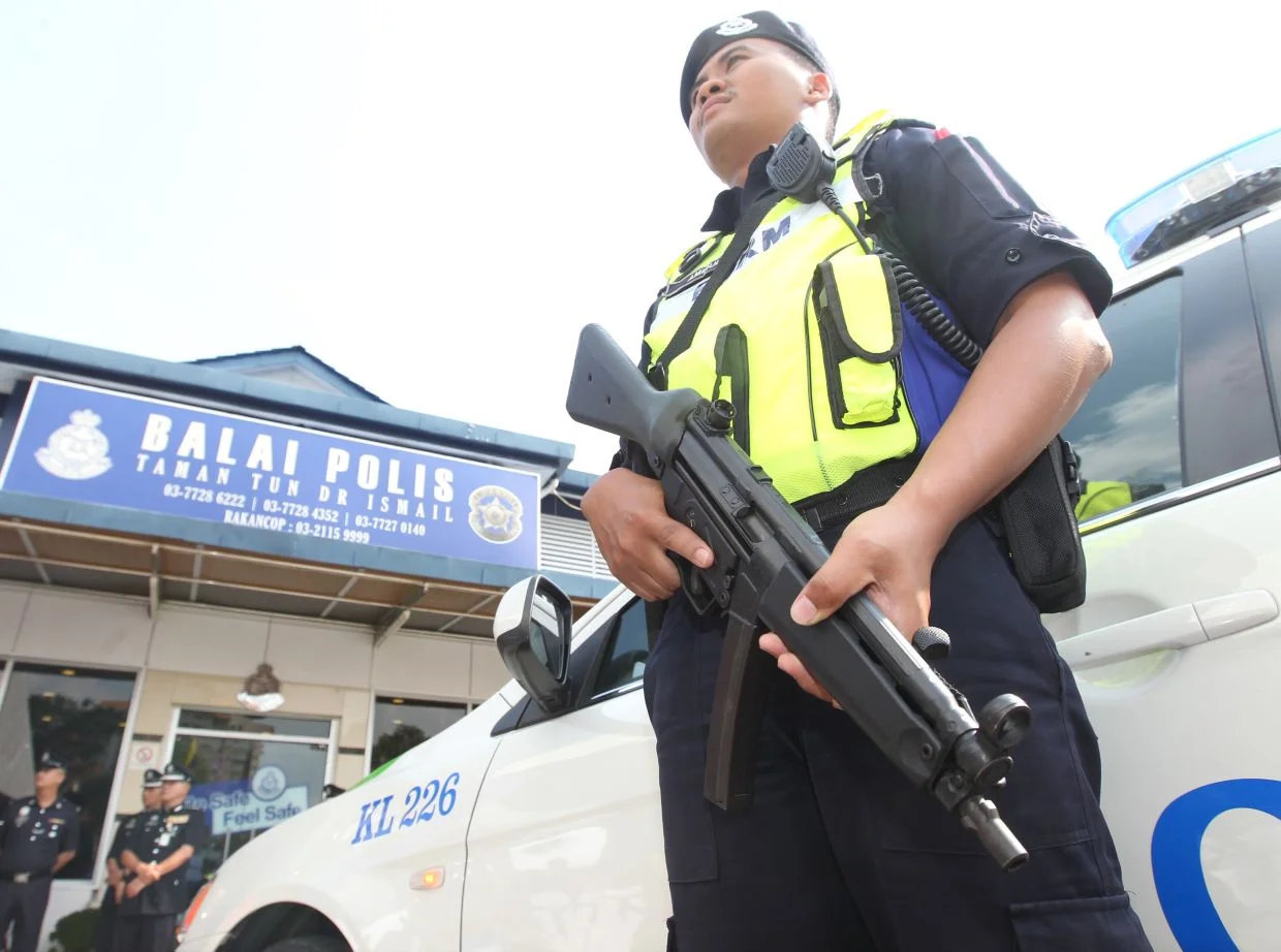 Police patrol personnel standing guard at Taman Tun  Dr Ismail police station.