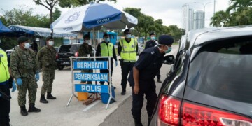 Seri Alam OCPD Supt Ismail Dollah (looking into car window) visiting a roadblock in Seri Alam and conducting checks on drivers to ensure they obey the Movement Control Order.