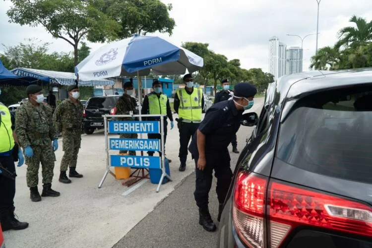 Seri Alam OCPD Supt Ismail Dollah (looking into car window) visiting a roadblock in Seri Alam and conducting checks on drivers to ensure they obey the Movement Control Order.
