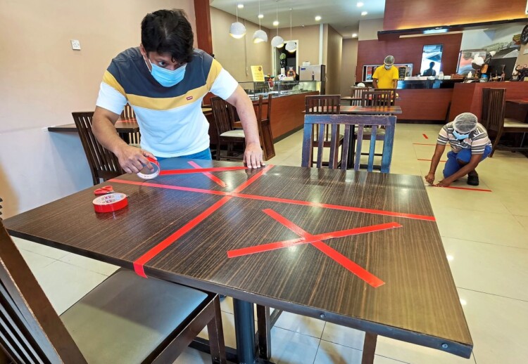 Manager of Restoran Grand Neelas, J. Neelavanen at Bandar Puchong Jaya marking up table with crosses to maintain table distancing and social distancing as restaurant were allowed to reopen for dine-ins under the conditional movement control order (MCO). YAP CHEE HONG / The Star.
