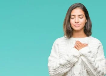 woman in white sweater holding hands over heart gratitude concept