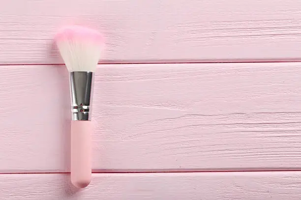 Makeup brush on a pink wooden background