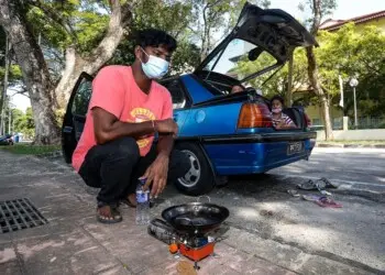 PENANG 24/12/2020: S. Ganesh (middle), 33 pictured with his family as they spent their days living in their car after their house caught on fire here at Padang Polo on December 24th. PICTURE BY SAYUTI ZAINUDIN